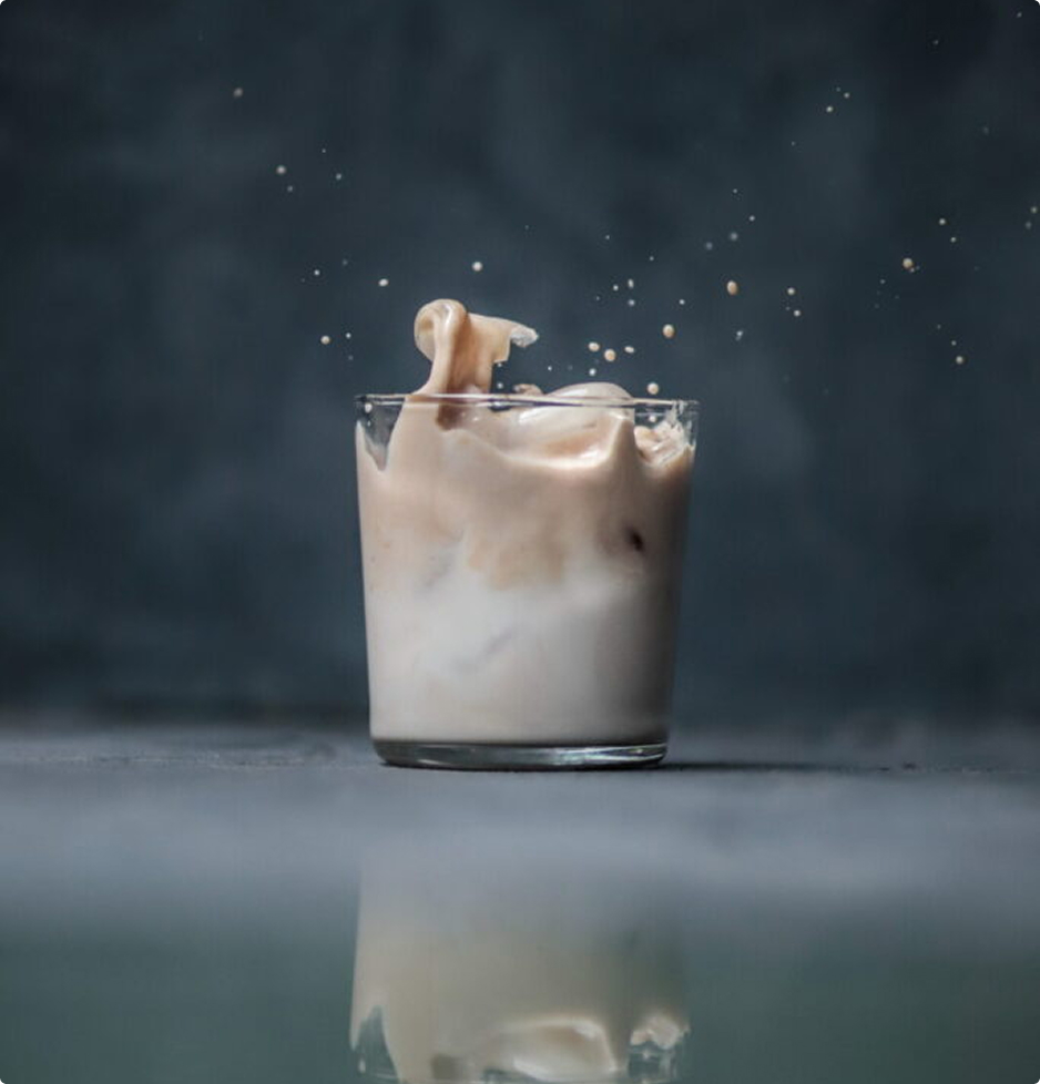 Verre de sticky chai glacé avec du lait en mouvement lors de la préparation