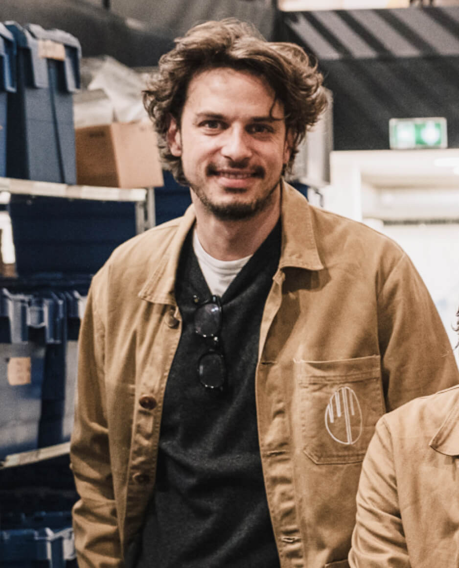 Personne debout souriante portant une veste claire dans un espace de travail