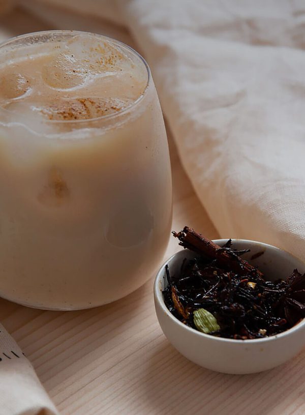 Iced chai latte servi dans un verre avec des glaçons, accompagné de chai en feuilles
