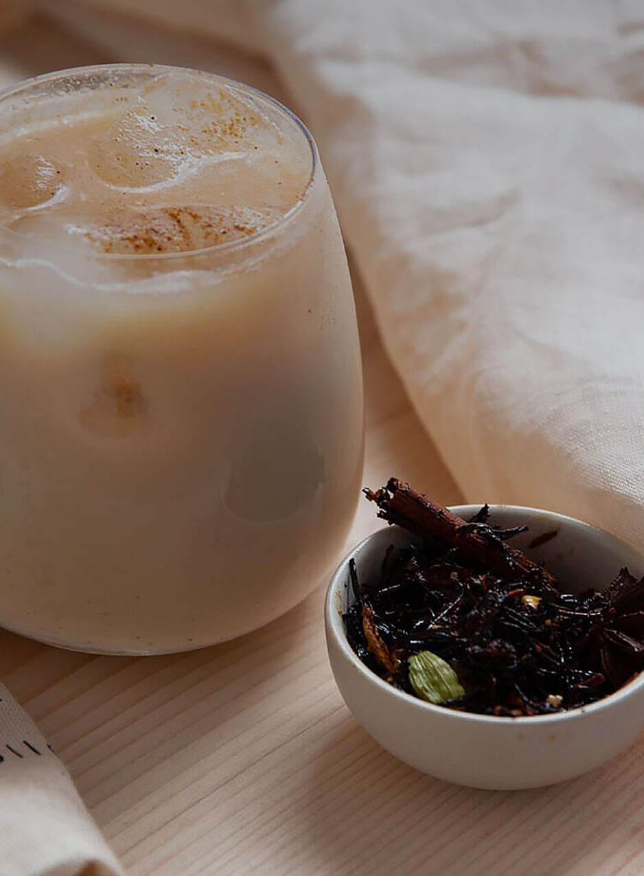 Iced chai latte servi dans un verre avec des glaçons, accompagné de chai en feuilles