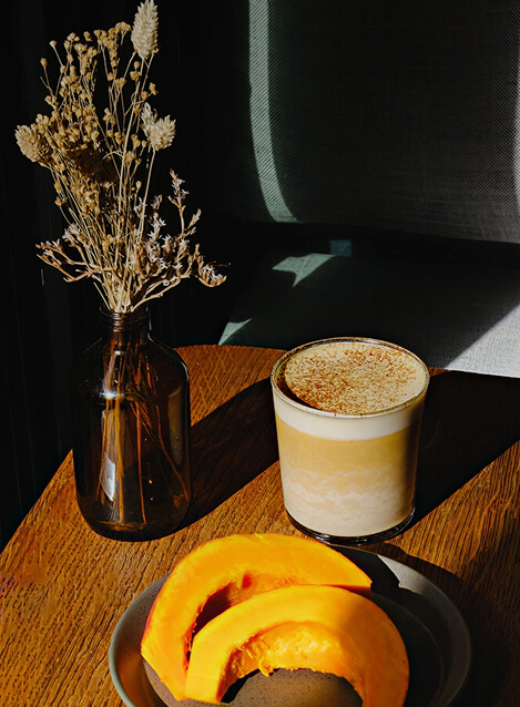 Pumpkin chai latte servi dans un verre, accompagné de tranches de courge