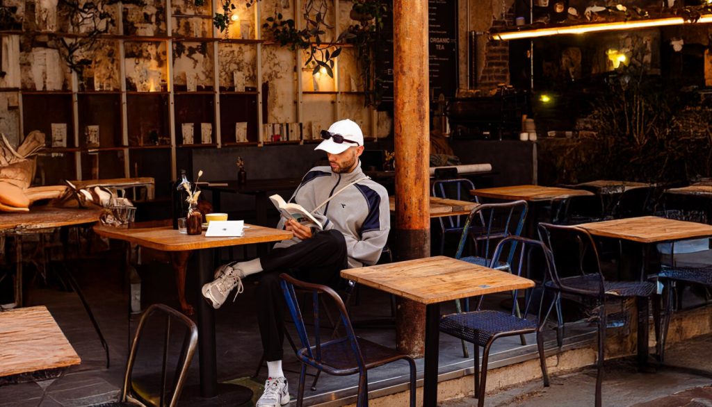 Personne assise à une table lisant un livre dans un coffee shop au mobilier en bois