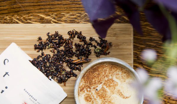 Préparation de honeybush avec feuilles de thé sur une planche et boisson servie dans une tasse